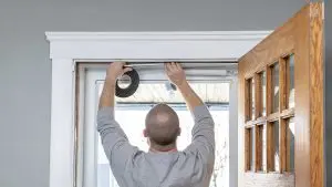man replaces weatherstripping in door frame