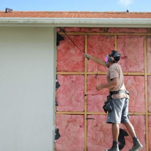 Builder removing old fiberglass wall insulation.Home improvement companies traded asbestos insulation for fiberglass after finding out the harmful effects asbestos has on lungs.